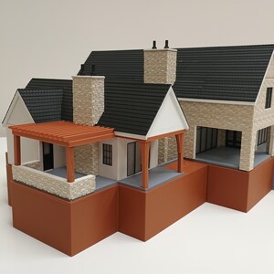 May include: A detailed architectural scale model of a house featuring a black shingled roof, light-colored stone exterior walls, and a brown wooden pergola over a patio area. The structure sits on a solid, stepped brown base with visible chimneys.