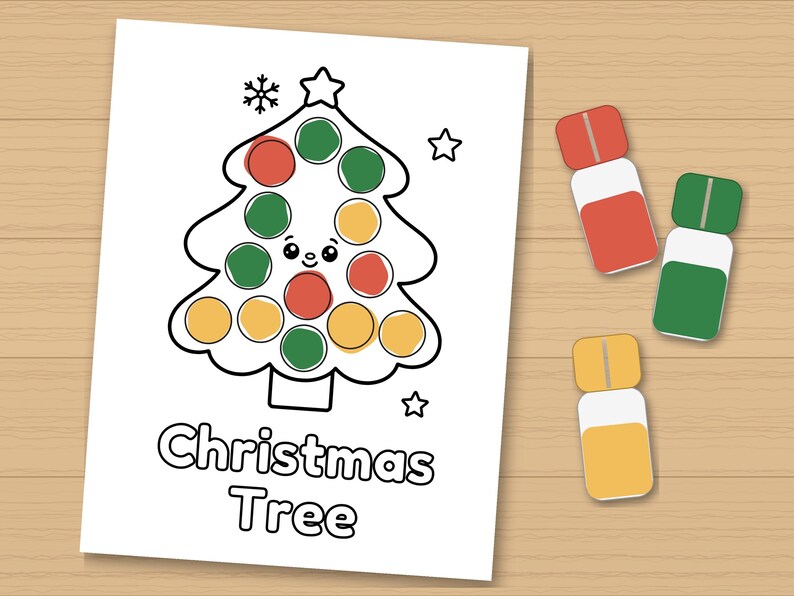 May include: A white colouring page featuring a black outline of a Christmas tree with a smiling face, decorated with red, green, and yellow circular dots. The text Christmas Tree is printed below. Three small rectangular paint daubers are nearby.
