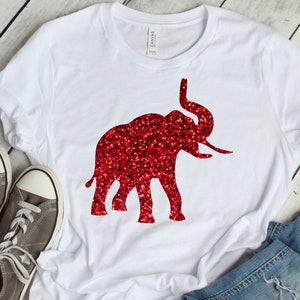 May include: White t-shirt with a red glitter iron-on transfer of an elephant. The text "Iron on transfer only!" is printed below the image.