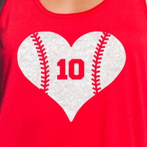 May include: Red tank top with a white heart-shaped baseball design with the number 10 in the centre. The heart is covered in glitter.