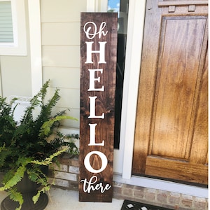 May include: A wooden sign with the words "Oh Hello there" painted in white on a dark brown background.