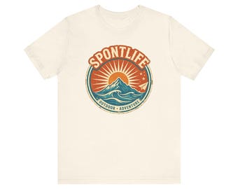 May include: A cream-colored short-sleeve t-shirt featuring a circular graphic on the chest. The design displays a mountain peak, ocean waves, and a sunburst in orange and blue, with the text SPONTLIFE OUTDOOR ADVENTURE and a paper airplane.