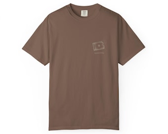 May include: A solid brown short-sleeve t-shirt with a crew neckline. On the left chest area, there is a small, light-colored rectangular graphic featuring a central star-like shape and the text "spuntlife" printed in a simple, lowercase font.