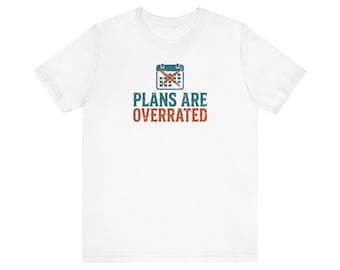 May include: A white short-sleeve t-shirt featuring a graphic of a calendar with a large orange X across it. Below the calendar, the text reads PLANS ARE OVERRATED in teal and orange block letters with a distressed, vintage-style texture.