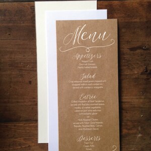 May include: A menu card with a kraft paper background and white text. The menu includes appetizers, salad, entree, and desserts. The menu is displayed with a white and cream-colored card on a wooden surface.