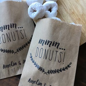 May include: Two brown paper bags with the text "mmm... DONUTS!" printed on them. The bags are decorated with a wreath of leaves and the text "Amelia & Jason" and "JUNE 17, 2017".