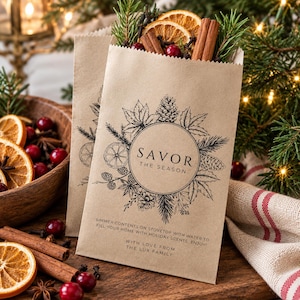 May include: Two light brown paper bags filled with dried orange slices, cinnamon sticks, pine sprigs, and cranberries. The bags feature a black botanical illustration, a circular frame, and the text SAVOR THE SEASON with instructions.