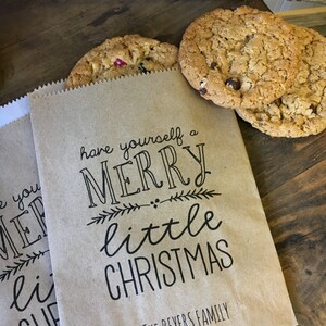 May include: Two brown paper bags with the text "have yourself a merry little christmas" and "The Beyers Family" printed on them. The bags are filled with cookies.