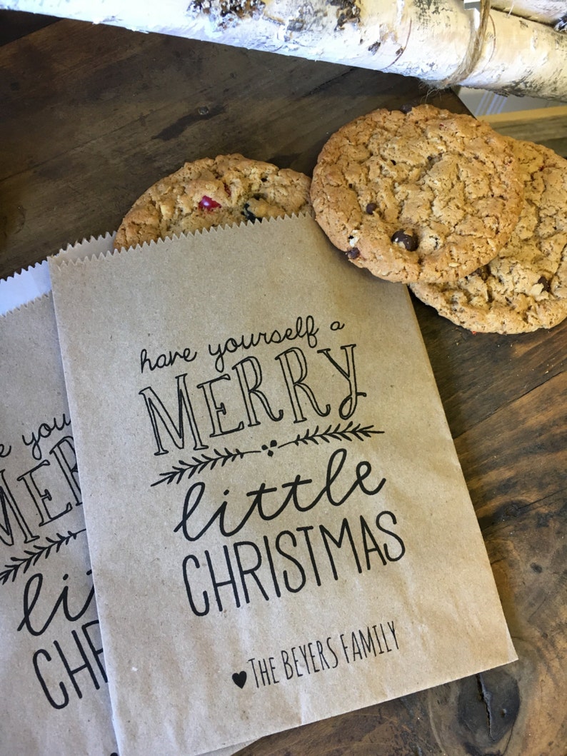 May include: Two brown paper bags with the text "have yourself a merry little christmas" and "The Beyers Family" printed on them. The bags are filled with cookies.