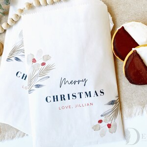 May include: Two white paper gift bags with a watercolour design of leaves and berries. The bags have the text "Merry Christmas" and "Love, Jillian" printed on them.