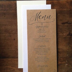May include: A rustic menu card with the word "Menu" in elegant script at the top. The menu is printed on a brown card with a white and cream-colored card behind it. The menu lists appetizers, salad, entree, and desserts.