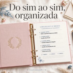 Könnte beinhalten: Ein rosafarbener Hochzeitsplaner mit Ringbindung und einem goldenen Kranz auf dem Einband. Die offene Seite zeigt eine 12-monatige Hochzeits-Checkliste mit portugiesischem Text, inklusive Abschnitten für 12, 11, 10, 9 und 8 Monate vor dem Termin.
