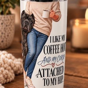 Könnte beinhalten: Ein weißer zylindrischer Becher mit transparentem Deckel, bedruckt mit einer Person in beigem Pullover und blauer Jeans, die eine Kaffeetasse neben einem Cane Corso Hund hält. Der Text lautet: I LIKE MY COFFEE HOT AND MY CORSO ATTACHED TO MY HIP.