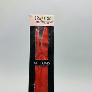 May include: A 12-inch red zipper in a black and white package. The package has a price tag that reads "12 in $1.00 136-C DEVIL RED" and the text "J.S.P. COATS".