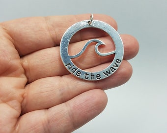 May include: Silver charm with a wave cut-out and the words "Ride the Wave" engraved around the edge.
