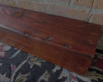 May include: A rectangular wooden beam with a rich, dark brown finish and a prominent natural wood grain pattern. The surface displays visible knots and textured imperfections, showcasing the organic character of the timber material.