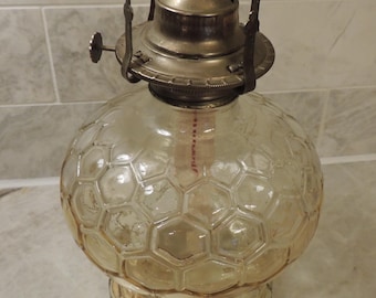 May include: A vintage glass oil lamp with a clear, textured globe and a silver-toned metal burner. The globe has a honeycomb pattern.