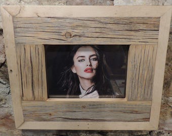 May include: A rustic wooden picture frame with a light brown finish. The frame has a raised edge and a textured surface. A photo of a woman with long dark hair and red lipstick is inside the frame.