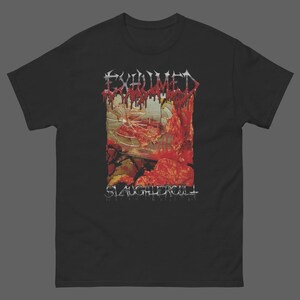 May include: A black short-sleeved t-shirt featuring a graphic print with the text EXHUMED at the top and SLAUGHTERCULT at the bottom. The central image depicts a shattered glass surface with red, blood-like splatters and organic textures.