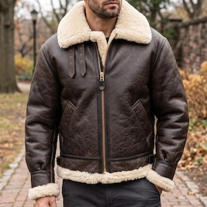 Peut inclure: Un blouson aviateur en cuir marron foncé doté d'un col et d'une doublure épais en peau lainée crème. La veste comprend une fermeture éclair frontale en laiton, deux pattes de serrage en cuir au col et des poignets en peau lainée.