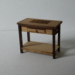 Könnte beinhalten: Ein kleiner Holztisch mit einer Schublade und einem Regal. Die Tischplatte hat ein geschnitztes Design.