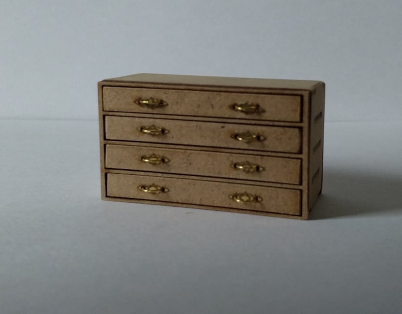 May include: A wooden dresser with five drawers and gold-colored handles. The dresser is made of light brown wood and has a simple design.