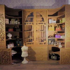 May include: A wooden cabinet with glass doors and shelves, filled with decorative items, including purses, bottles, and jewelry. The cabinet has intricate carvings and a distressed finish.