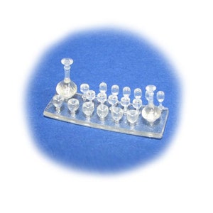 May include: A set of clear glass wine glasses and a decanter on a clear plastic tray. The glasses are arranged in rows and the decanter is in the center.