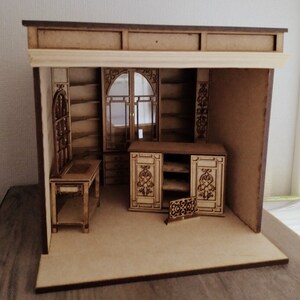 May include: A miniature wooden dollhouse room with a desk, shelves, and a cabinet. The room is made of light brown wood and has a dark brown trim. The room is empty except for the furniture.