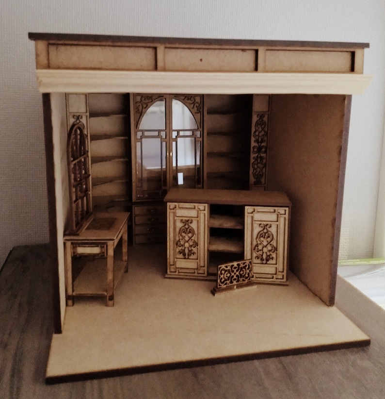 May include: A miniature wooden dollhouse room with a desk, shelves, and a cabinet. The room is made of light brown wood and has a dark brown trim. The room is empty except for the furniture.
