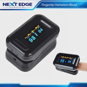 May include: A black fingertip pulse oximeter with a digital display showing SpO2 and BPM readings. The device features a glossy finish and a screen with blue and yellow text. The brand name NEXT EDGE SURGICAL is visible at the top of the image.