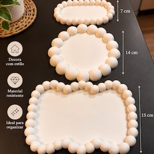 Könnte beinhalten: Drei weiße Dekotabletts mit Perlenrand. Das kleine ovale Tablett misst 14 cm mal 7 cm, das runde Tablett hat einen Durchmesser von 14 cm und das große rechteckige Tablett misst 21 cm mal 15 cm. Der Text enthält Decora com estilo.