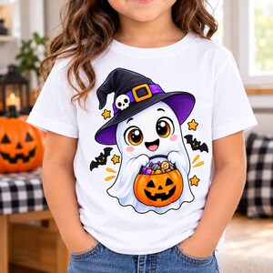 May include: A white t-shirt featuring a cartoon graphic of a white ghost wearing a black witch hat with a purple band, a yellow buckle, and a skull accent. The ghost is holding an orange jack-o'-lantern bucket filled with colourful candy.