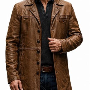 May include: A brown leather coat with a distressed finish, featuring a notched collar, a button-front closure, and a chest pocket. The coat is worn over a dark charcoal gray henley shirt and dark blue jeans with a brown leather belt.