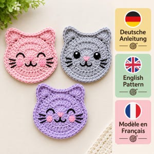 May include: Three crocheted cat-shaped coasters in pink, gray, and purple. Each features embroidered black eyes, whiskers, a mouth, and pink cheeks. To the right, three square icons display the text Deutsche Anleitung, English Pattern, and Modèle en Français.