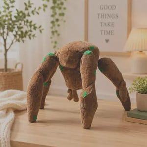 May include: A brown plush toy shaped like a four-legged creature with a textured surface resembling bark and small green circular patches. The figure has a rounded central body and four thick, jointed limbs that extend outward to support its weight.