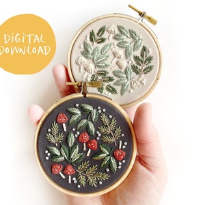 May include: Two embroidery hoop patterns, one with white mushrooms and green leaves on a beige background, and the other with red mushrooms and green leaves on a black background.