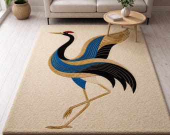 May include: A rectangular area rug with a cream-coloured background featuring a large, stylized crane bird design. The crane is depicted with a black neck, a red crown, and wings patterned in shades of blue, black, and gold, standing on thin legs.