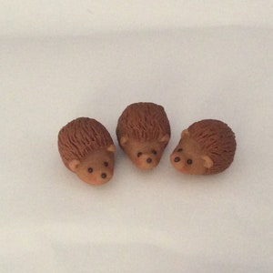 May include: Three small brown ceramic hedgehogs with black eyes.
