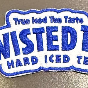 May include: An embroidered patch featuring the blue and white Twisted Tea logo with the text True Iced Tea Taste and Hard Iced Tea. The patch has a scalloped white border and bold blue lettering on a white background with a blue outline.