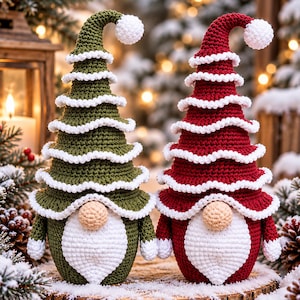 May include: Two crochet gnomes with tall, pointed hats featuring white ruffled trim. One gnome is olive green, the other is deep red. Both have round beige noses, white crochet beards, and white pom-poms at the tips of their hats.