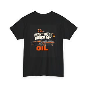 May include: A black short-sleeve t-shirt featuring a graphic of a grey muscle car with orange stripes. Above the car is an orange oil dipstick icon and the text "I WANT YOU TO CHECK MY" in white, with the word "OIL" in large orange letters below.
