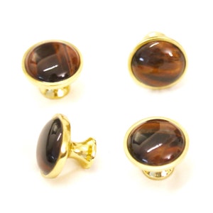 Puede incluir: Cuatro pomos de armario dorados con incrustaciones redondas de ojo de tigre.