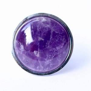 May include: A round, silver-toned knob with a purple amethyst stone inset.