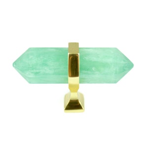 May include: A green crystal cabinet knob with a gold metal base. The crystal is shaped like a long, pointed, double-ended prism.