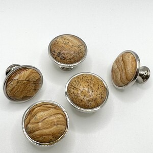 May include: Five round cabinet knobs with a silver metal base and a brown and beige marbled stone top.