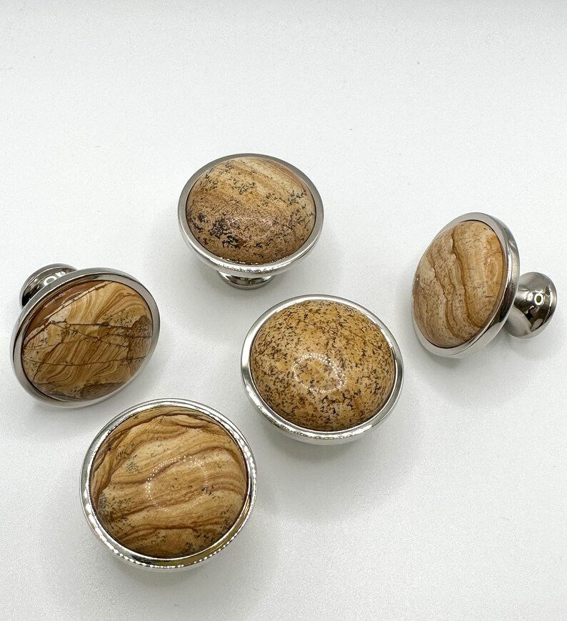 May include: Five round cabinet knobs with a silver metal base and a brown and beige marbled stone top.