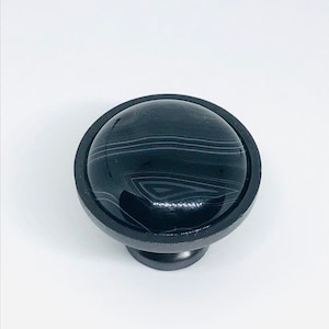 May include: Black round cabinet knob with a black and white marbled design.