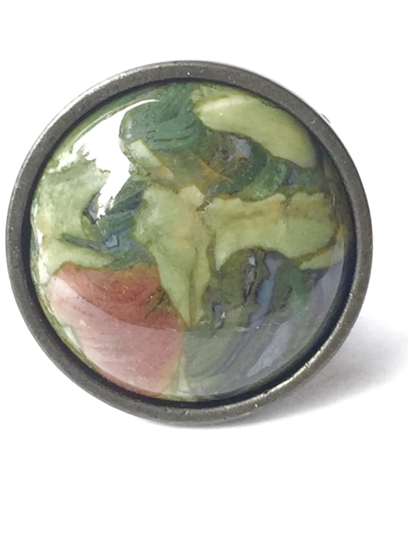 May include: A round, green, brown, and white patterned cabochon set in a silver-toned metal ring.