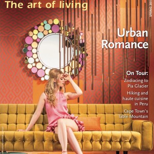 May include: A magazine cover featuring a woman sitting on a yellow tufted sofa. The cover features the text "HOMEFRONT The art of living" and "Urban Romance". The magazine cover also features the text "On Tour: Zodiacing to Pia Glacier Hiking and haute cuisine in Peru Cape Town's Table Mountain".